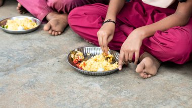 PUDUCHERRY, TAMIL NADU, Hindistan - Aralık 2018. Tanımlanamayan yoksul sınıf arkadaşları üniformalı çocuklar dışarıda oturuyorlar ve sağ elleriyle biraz pirinç yiyorlar. Sağlıksız öğle yemeği
