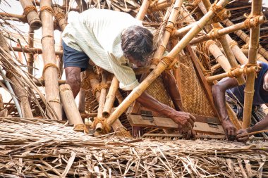 Çapulcu, TAMIL NADU - Aralık 2018. Tanımlanamayan Hintli işçiler turistlere servis yapmak için odunluğun tepesini hindistan cevizi yapraklarıyla kapladılar. Dalit halkı için zor bir iş.