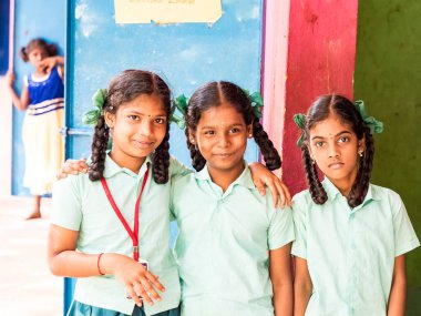Puducherry, Hindistan - Aralık yaklaşık, 2018. Kimliği belirsiz en iyi çocuk kız arkadaş sınıf ile ayakta gülümseyen hükümet okul üniformalı omzuna elini. Dostluk zevk çok ırklı schoolchilds portresi.