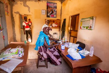 Bour, Senegal - Aralık 2021 civarı. Köydeki dispanser sağlık merkezinde kimliği belirlenemeyen insanlar ucuz teçhizatla küçük ilkel bir bölgede konsültasyon bekliyorlar. Afrika 'da yoksulluk