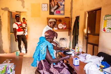 Bour, Senegal - Aralık 2021 civarı. Köydeki dispanser sağlık merkezinde kimliği belirlenemeyen insanlar ucuz teçhizatla küçük ilkel bir bölgede konsültasyon bekliyorlar. Afrika 'da yoksulluk