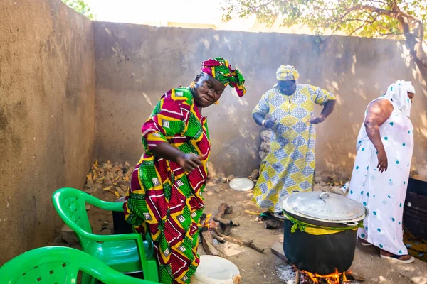 Bour, Senegal - Aralık 2021 civarı. Geleneksel renkte giyinmiş, tanımlanamayan kadınlar açık mutfakta temel gıdalarla yemek pişiriyorlar ama harika yemekler yapıyorlar. Afrika 'da yoksulluk