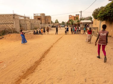 Bour, Senegal, Afrika, Aralık 2021 'de. Kimliği belirsiz Afrikalı çocuklar sokakta çuval yarışı yapıyor. Başlamak için havuzu suyla doldurmaları gerekiyor. Takım sporu çok komik.