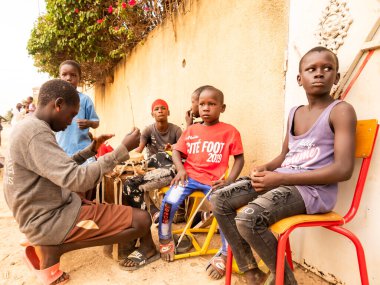 Bour, Senegal - Aralık 2021 civarı. Bir grup kimliği belirsiz çocuk, genç sokak müzisyenleri köyde müzik davulcusu. Çoğunlukla Afrika 'daki yoksullar için bir oyun.