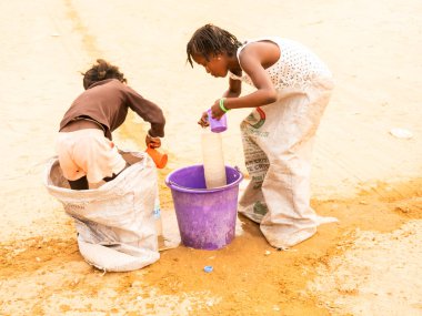 Bour, Senegal, Afrika, Aralık 2021 'de. Kimliği belirsiz Afrikalı çocuklar sokakta çuval yarışı yapıyor. Başlamak için havuzu suyla doldurmaları gerekiyor. Takım sporu çok komik.
