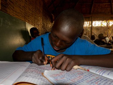 Bour, Senegal - Aralık 2021 civarı. Avrupa STK 'sı ona okul ve aile yemeği ödemesinde yardım ettiği için vaftiz babası veya vaftiz anasına mektup yazan kimliği belirsiz genç bir çocuk. Ellere yakın çekim