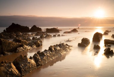rocks on the berocks on the beach sand under a red sunset light in the Basque Country, Spain