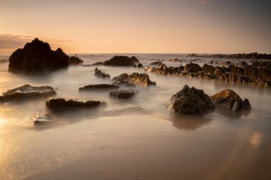 rocks on the berocks on the beach sand under a red sunset light in the Basque Country, Spain