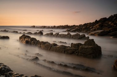 rocks on the berocks on the beach sand under a red sunset light in the Basque Country, Spain
