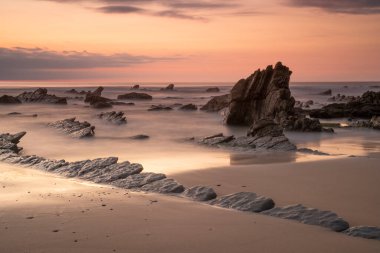 rocks on the berocks on the beach sand under a red sunset light in the Basque Country, Spain