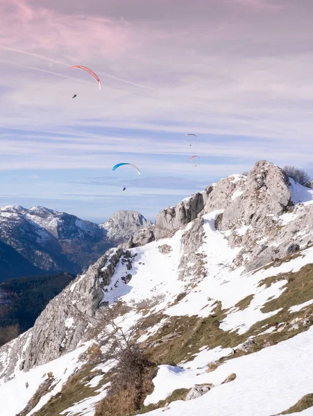 paragliders gliding over the mountains in winter at sunset. High quality photo
