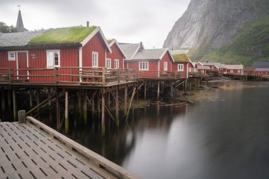 Norveç 'in Lofoten adalarındaki Reine balıkçı köyündeki balıkçı kulübeleri. Arkaplanda dağlar