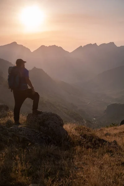 man standing on a mountain summit looking to the red sunset. High quality photo