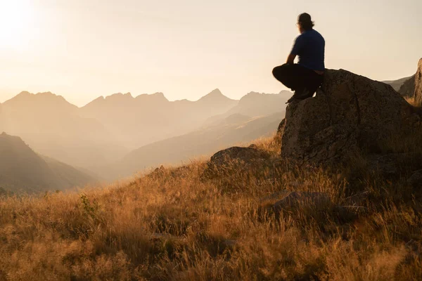 man standing on a mountain summit looking to the red sunset. High quality photo