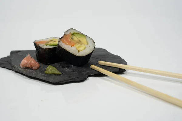 Tahta bir tabakta iki parça suşi, yemek çubuğu, zencefil ve wasabi. Yüksek kalite fotoğraf