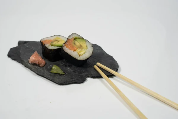 Tahta bir tabakta iki parça suşi, yemek çubuğu, zencefil ve wasabi. Yüksek kalite fotoğraf