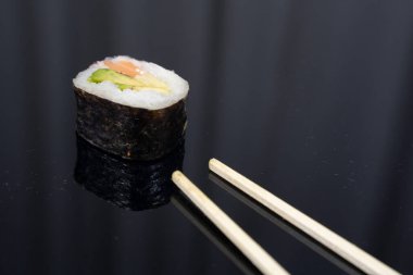 Koyu arkaplanda yemek çubukları olan bir parça suşi. Yüksek kalite fotoğraf