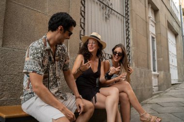 Bir grup arkadaş sokakta bir bankta eğleniyor ve gülüyorlar. Yüksek kalite fotoğraf