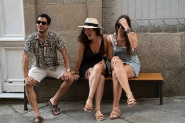 Bir grup arkadaş sokakta bir bankta eğleniyor ve gülüyorlar. Yüksek kalite fotoğraf