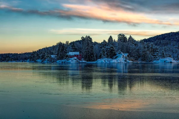 Ice covered fjord and colorful sky reflected in the ice. Winter landscape with islands, huts, sea, snowy rocks, blue sky, reflection at sunset. , Norway at dusk. Nature — Zdjęcie stockowe