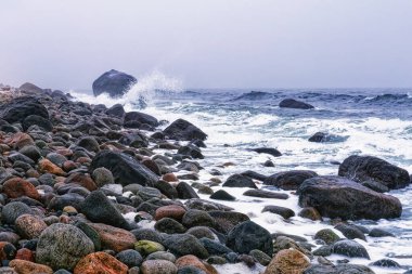 Molen plajında renkli yuvarlanan taşlarla fırtınalı ve bulutlu bir deniz manzarası. Larvik yakınlarındaki UNESCO Global Geopark, Vestfold County, Norveç