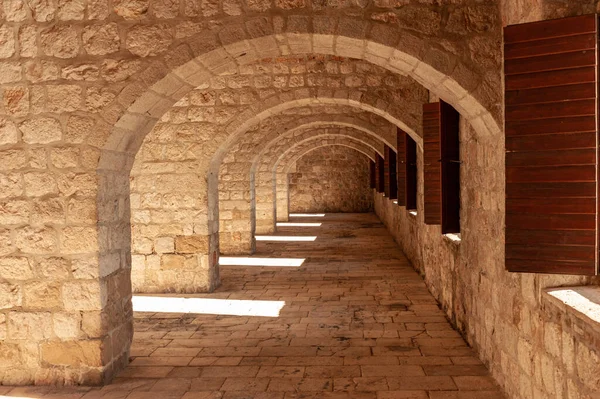 Interior fortification of brick arches receding to a vanishing point at Fort Lovrijenac, Dubrovnik, Croatia