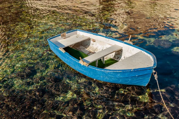 Küçük mavi ve beyaz Dingy kayığı kristal berrak deniz koyundaki bir rıhtıma demirlemiş..