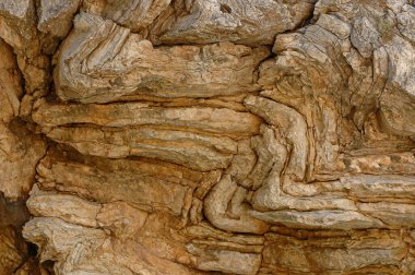 Kuru kahverengi, bronz tenli ve paslı kayalar zikzak çiziyor..