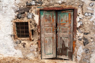 Eski paslı, çürük ve yıpranmış kapı ve pencere kaba dokulu taş duvarlı..