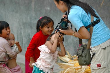DSLR kameralı kadın fotoğrafçı çok heyecanlı Miao köyü çocuklarıyla fotoğraf paylaşıyor. 