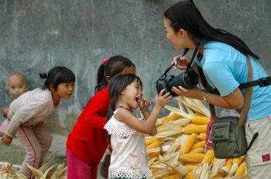 Kadın fotoğrafçı heyecanlı ve mutlu Miao köyü çocuklarıyla DSLR kamerasında fotoğraf paylaşıyor.