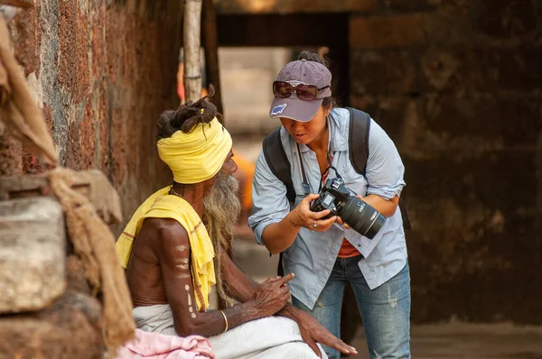 Woman photographer sharing photos on her DSLR camera with Indian man