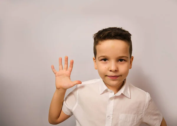 Çocuk duygusal neşesini bir gülümsemeyle gösterir. Stüdyodaki beyaz gömlekli çocuk farklı duygularını gösterir. Bu duygu dokuz yaşındaki bir çocuk tarafından gösterilir..