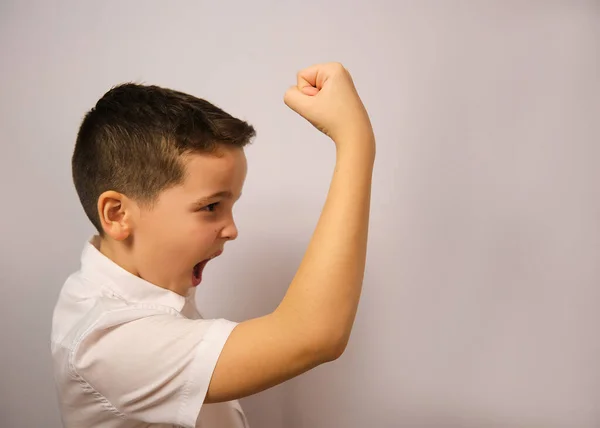 The boy shows his emotion anger raises his hand and shouts The boy in the studio in a white shirt shows his different emotions.The emotion is shown by a child of nine years old.