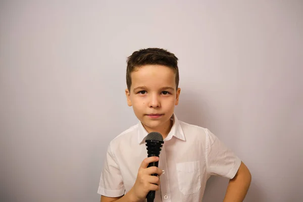 Avrupalı çocuk duygularını gösteriyor. Elinde mikrofon olan beyaz gömlekli bir çocuk. Ne kadar sakin..