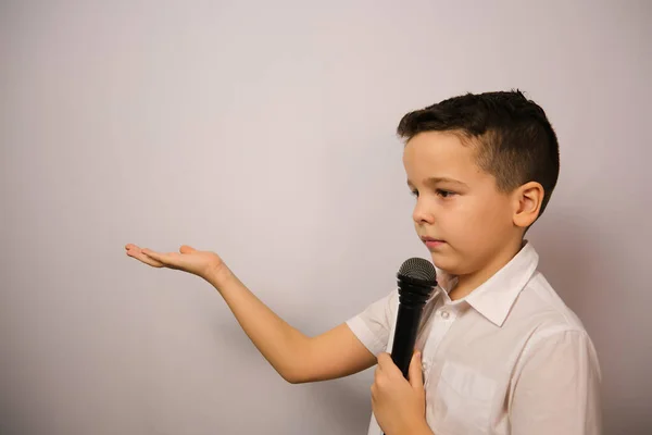 Avrupalı çocuk duygularını gösteriyor. Elinde mikrofon olan bir çocuk elini beyaz gömleğiyle uzatıyor. Doğrusunu söylemek gerekirse, dürüst bir adam.
