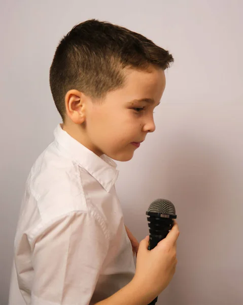 Menino Com Microfone Fundo Branco Uma Camisa Branca Olha Atentamente — Fotografia de Stock