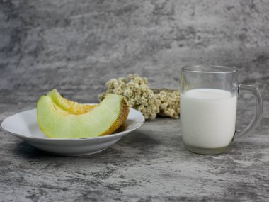 Bir bardak süt ve tabakta dilimlenmiş kavun. Sağlıklı gıda konsepti için