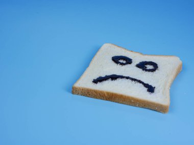 Mavi pastel arka planda hüzünlü bir ifade olan beyaz ekmek