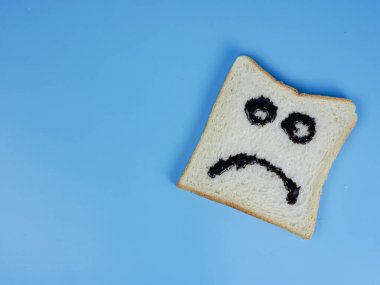Mavi pastel arka planda hüzünlü bir ifade olan beyaz ekmek