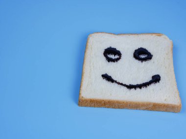 Mavi pastel arka planda gülen yüz ifadesi olan beyaz ekmek