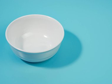 Mavi arka planda boş beyaz kase. minimalist stil.