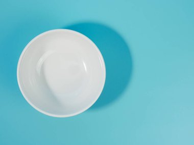 Mavi arka planda boş beyaz kase. minimalist stil.