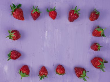 Strawberries on purple background top view. healthy and vegetarian fruit concept.
