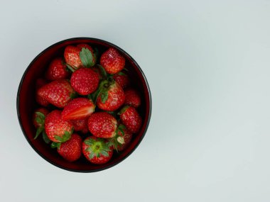 top view of strawberries in a bowl on white background. healthy fruit concept with copy space.