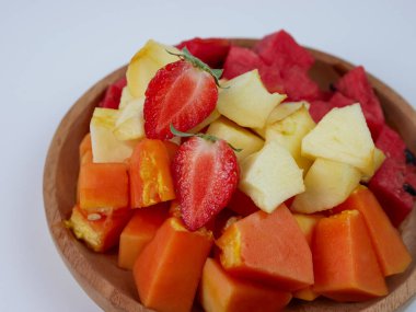 sliced strawberry, papaya, apple, and watermelon on a wooden plate on white background. healthy fruit concept