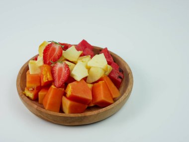 sliced strawberry, papaya, apple, and watermelon on a wooden plate on white background. healthy fruit concept