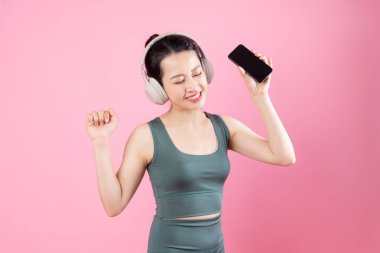 Asyalı fitness kızı portresi, pembe arka planda izole edilmiş.