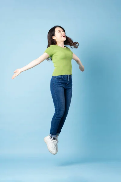 Asyalı güzel bir kızın portresi mavi arka planda tek başına zıplıyor.