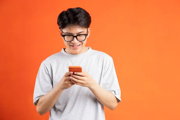 Cheerful Young Asian Man Using Phone Isolated Orange Background — Stock Photo, Image